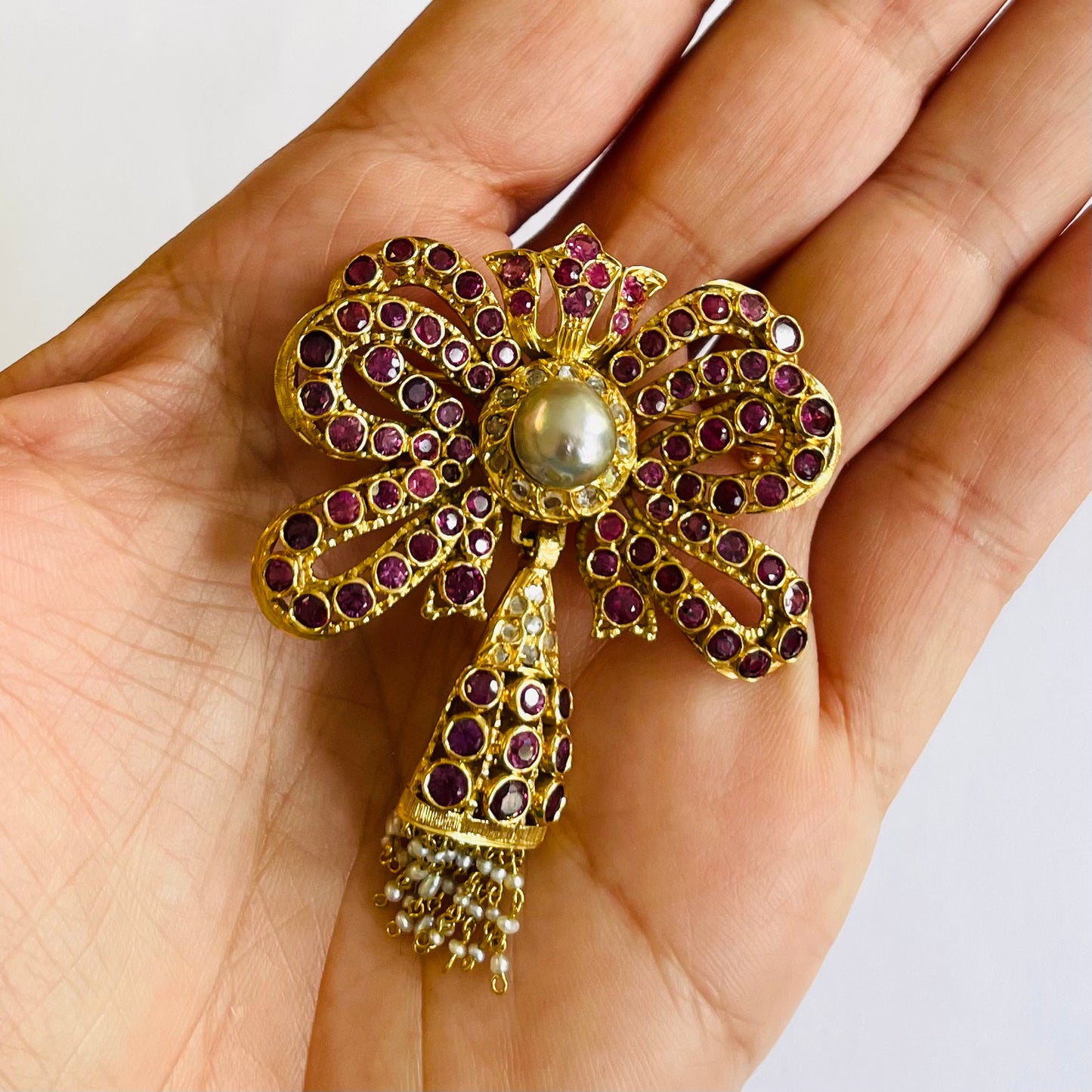 1960s 18KT Yellow Gold Ruby, Diamond & Cultured Pearl Bow Brooch in hand