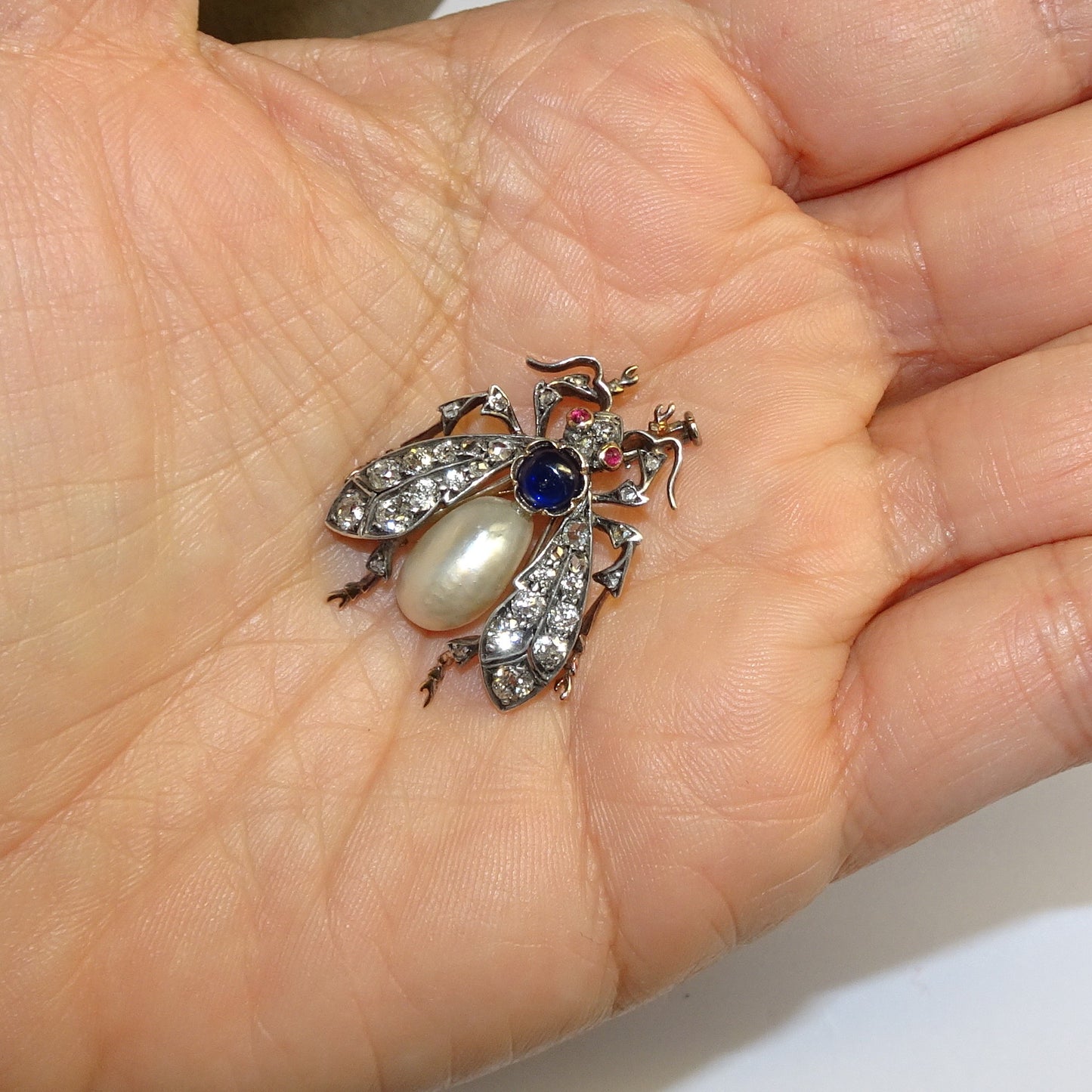 Victorian Silver & 18KT Yellow Gold Natural Pearl, Diamond, Ruby & Sapphire Fly Brooch in hand