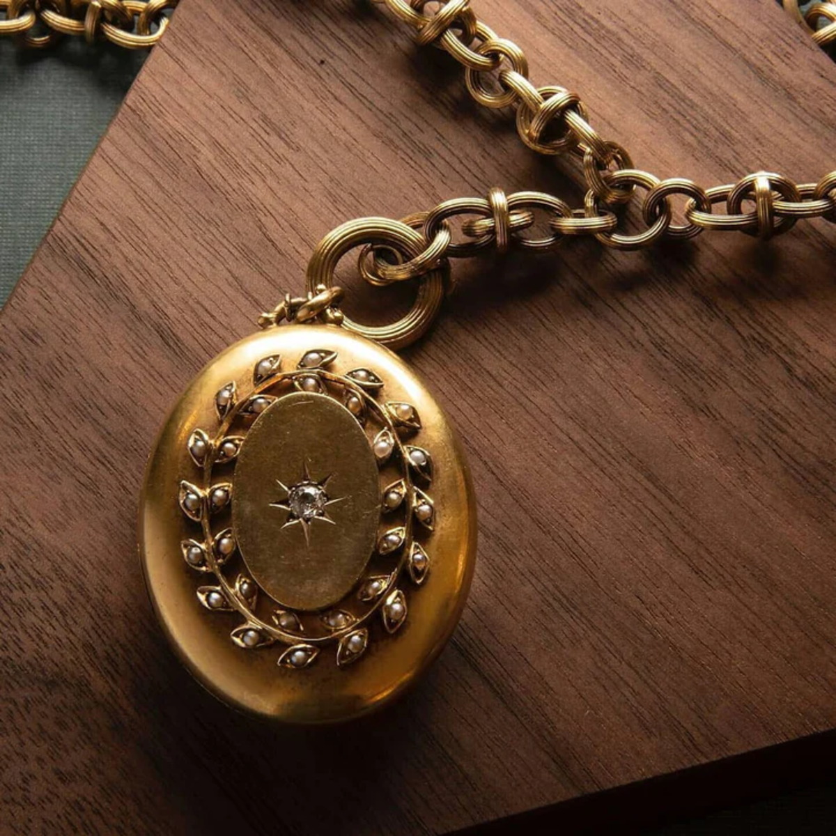 Victorian 18KT Yellow Gold Diamond & Seed Pearl Locket Necklace front view on desk