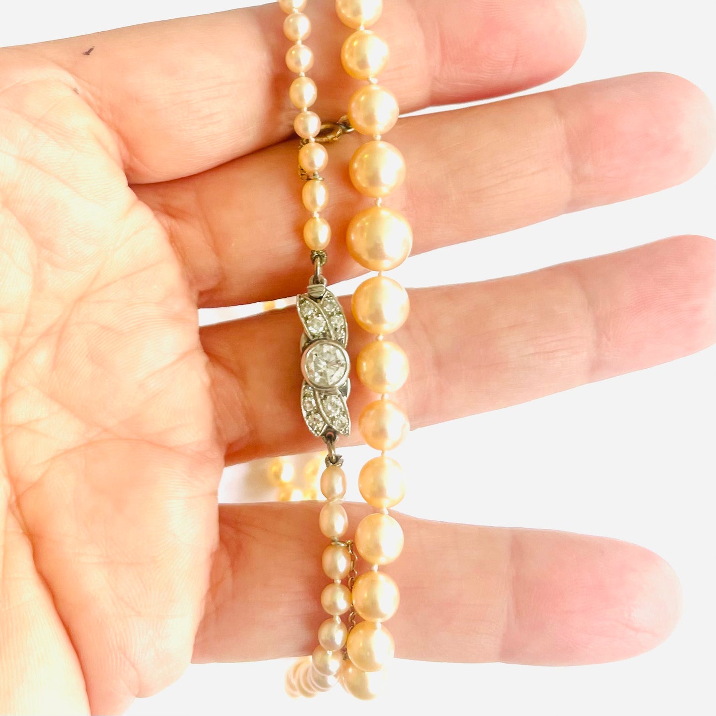 1930s Platinum Natural Pearl & Diamond Necklace in hand