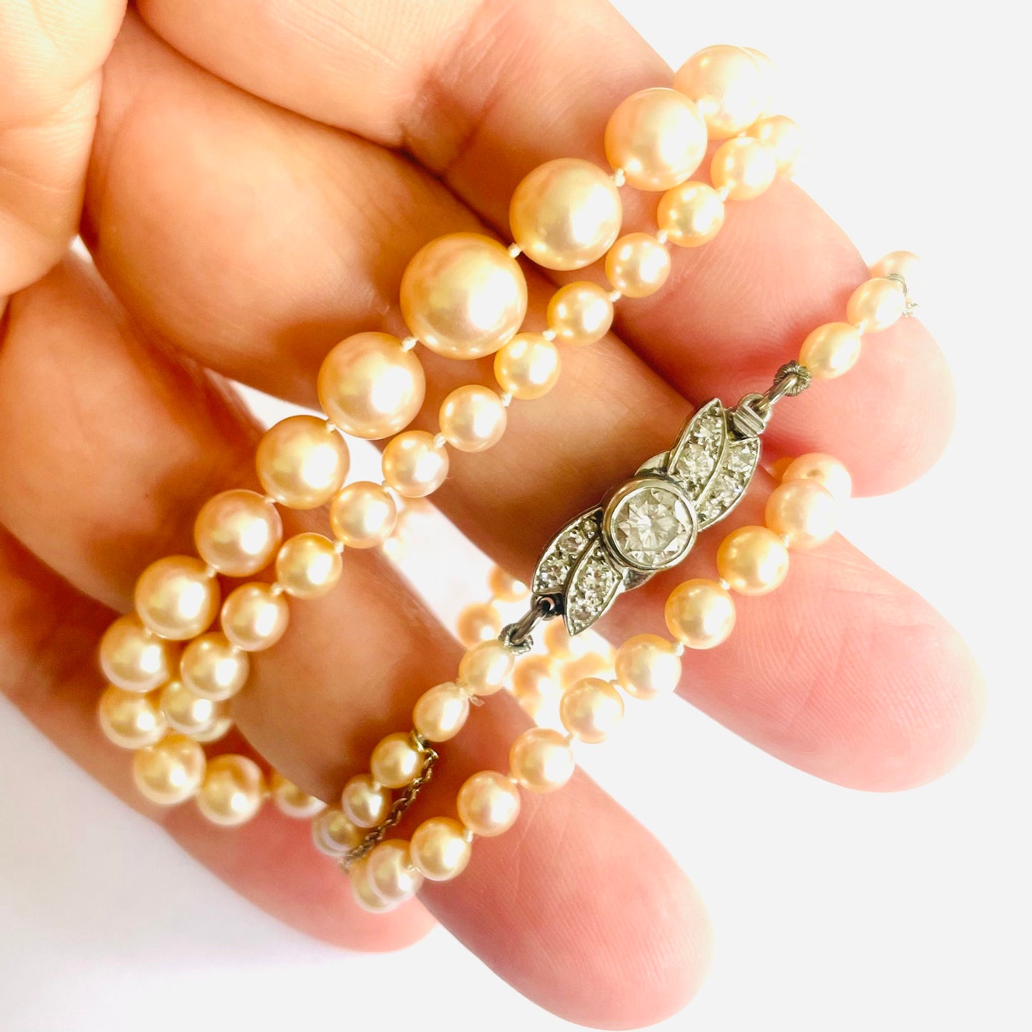 1930s Platinum Natural Pearl & Diamond Necklace in hand