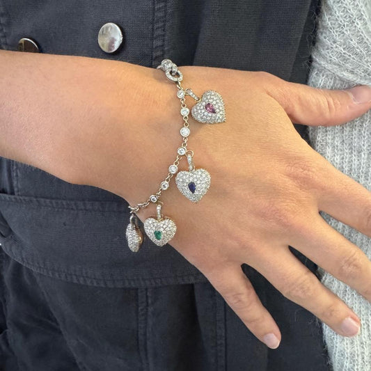 Diamond, emerald, amethyst, ruby, sapphire, rock crystal, tourmaline spell out the word dearest, 18-karat gold and platinum heart charm bracelet, circa 1970s.