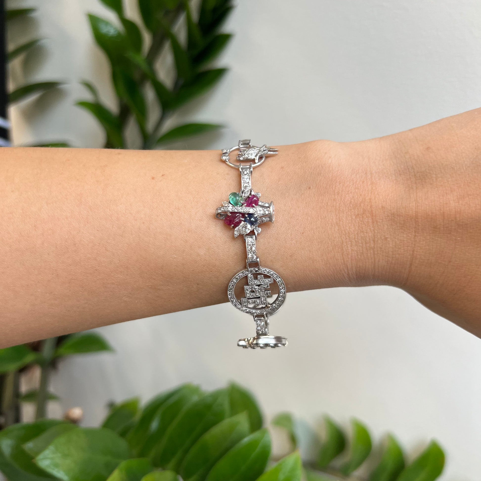 Art Deco Platinum Diamond, Emerald, Ruby & Sapphire Charm Bracelet worn on wrist