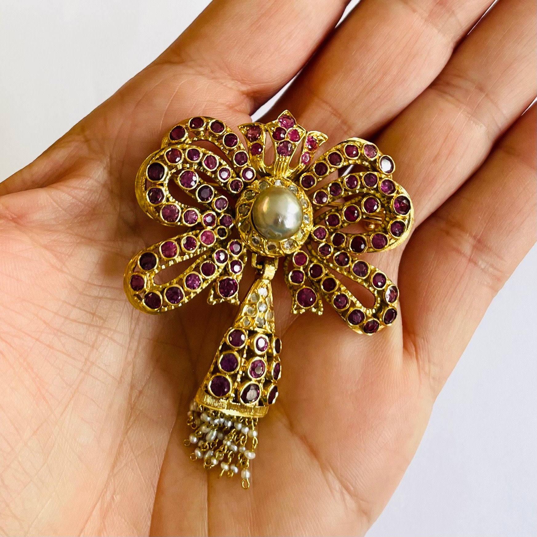 1960s 18KT Yellow Gold Ruby, Diamond & Cultured Pearl Bow Brooch in hand