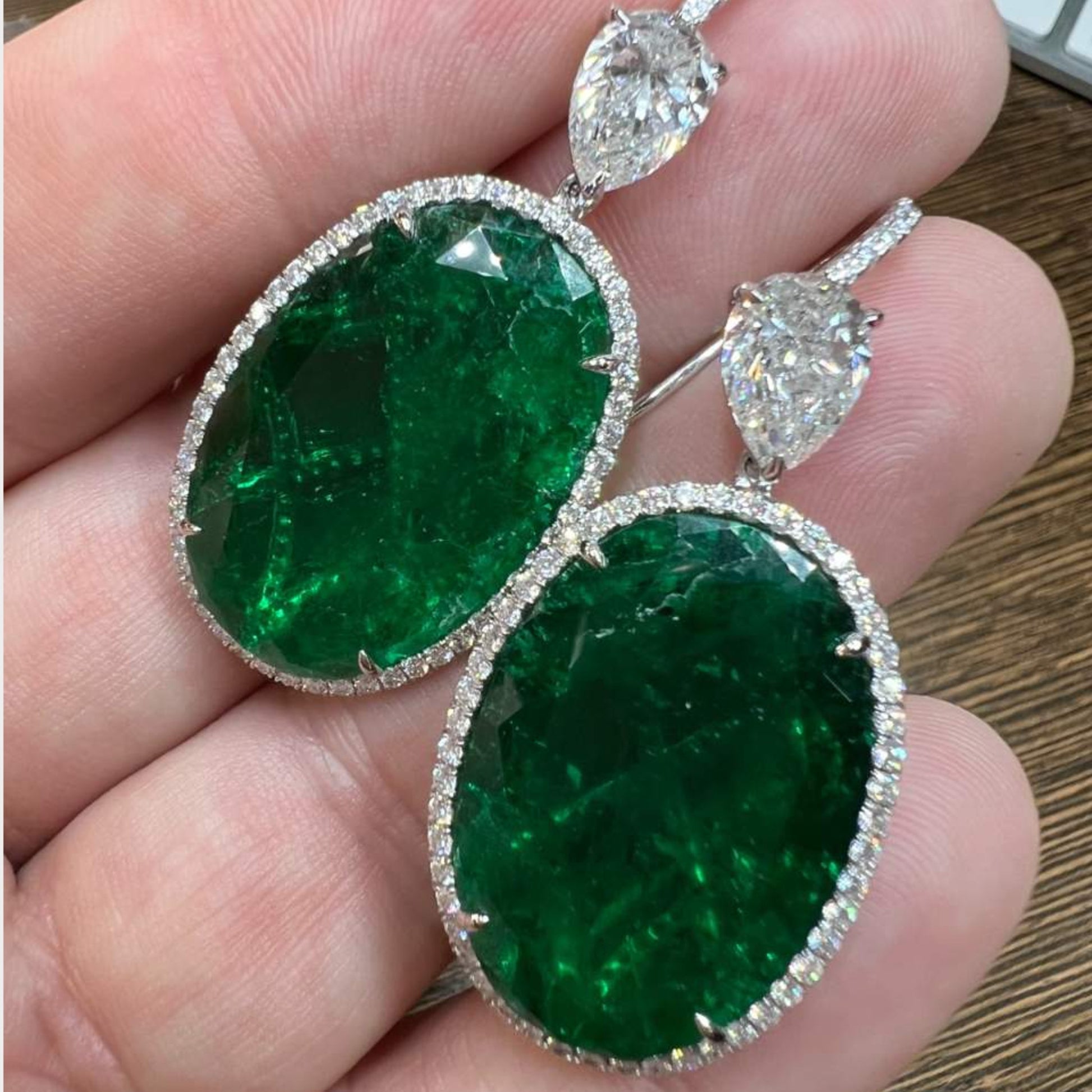 1990s Platinum Emerald & Diamond Earrings in hand