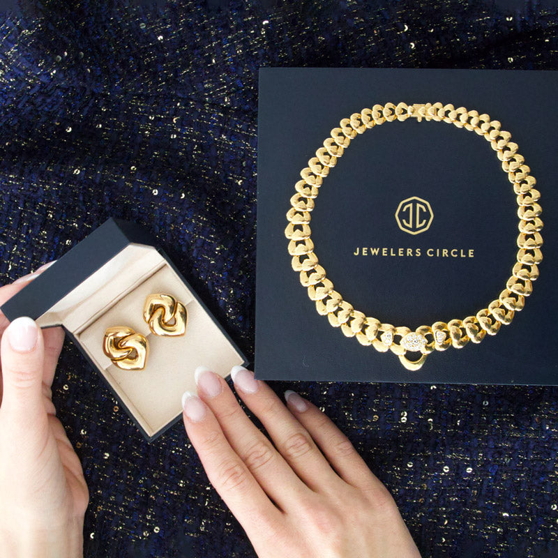 Gold chain bracelet on a 'Jewelers Circle' box with gold earrings in a box.