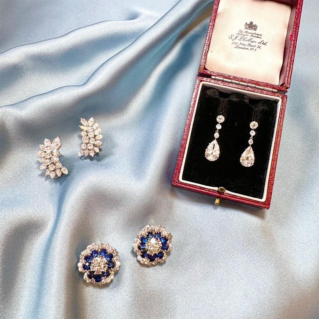 Set of earrings on a satin surface with a branded box.