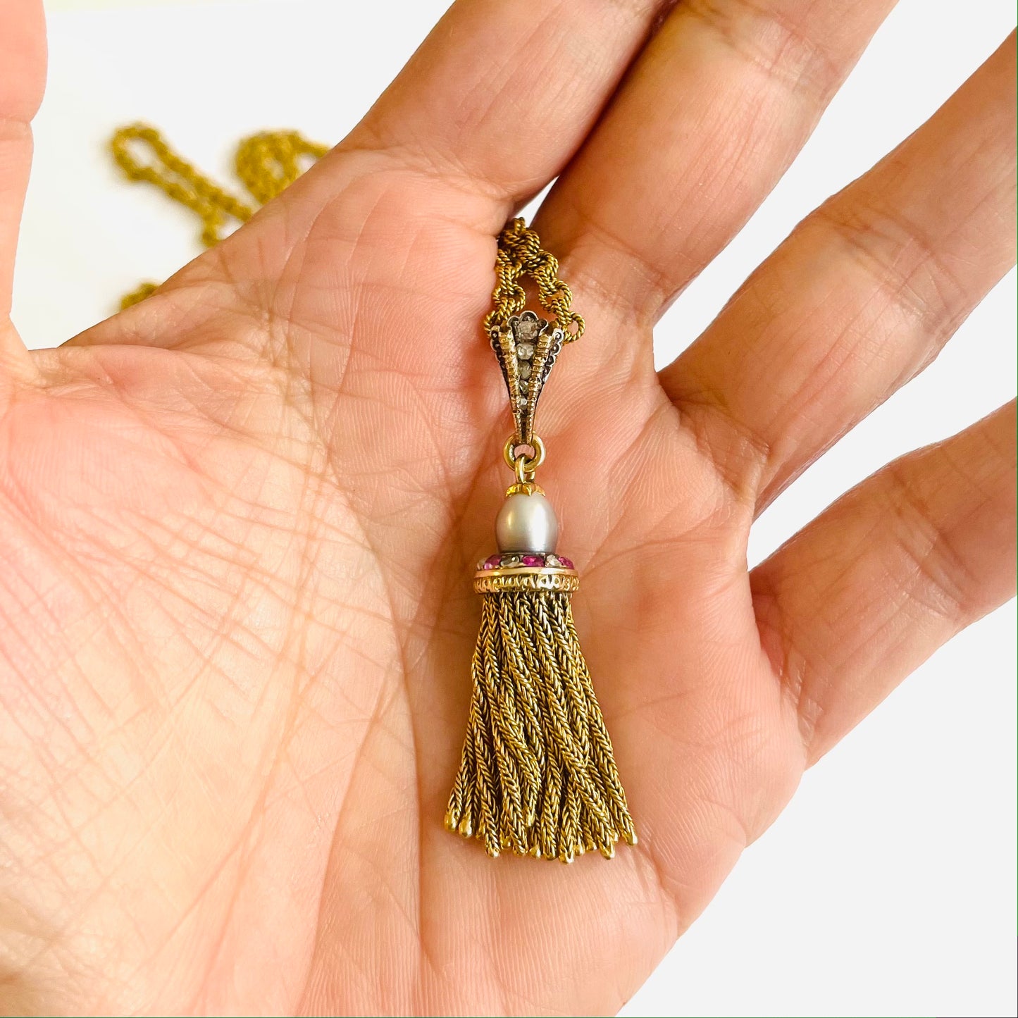 French Antique 18KT Yellow Gold Natural Pearl, Diamond & Ruby Tassel Pendant Necklace in hand