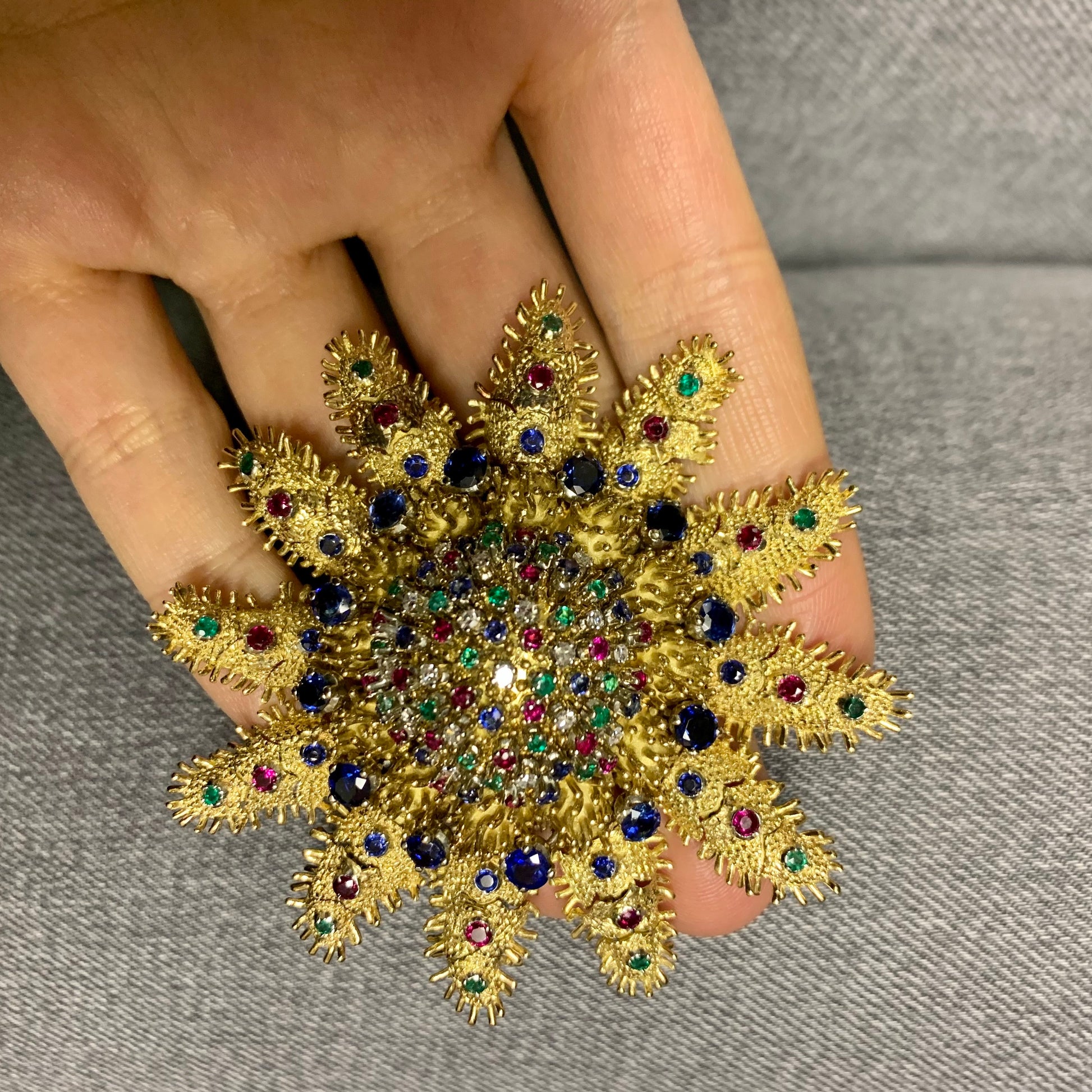 1960s 18KT Yellow Gold Diamond, Emerald, Ruby & Sapphire Articulated Starfish Brooch in hand