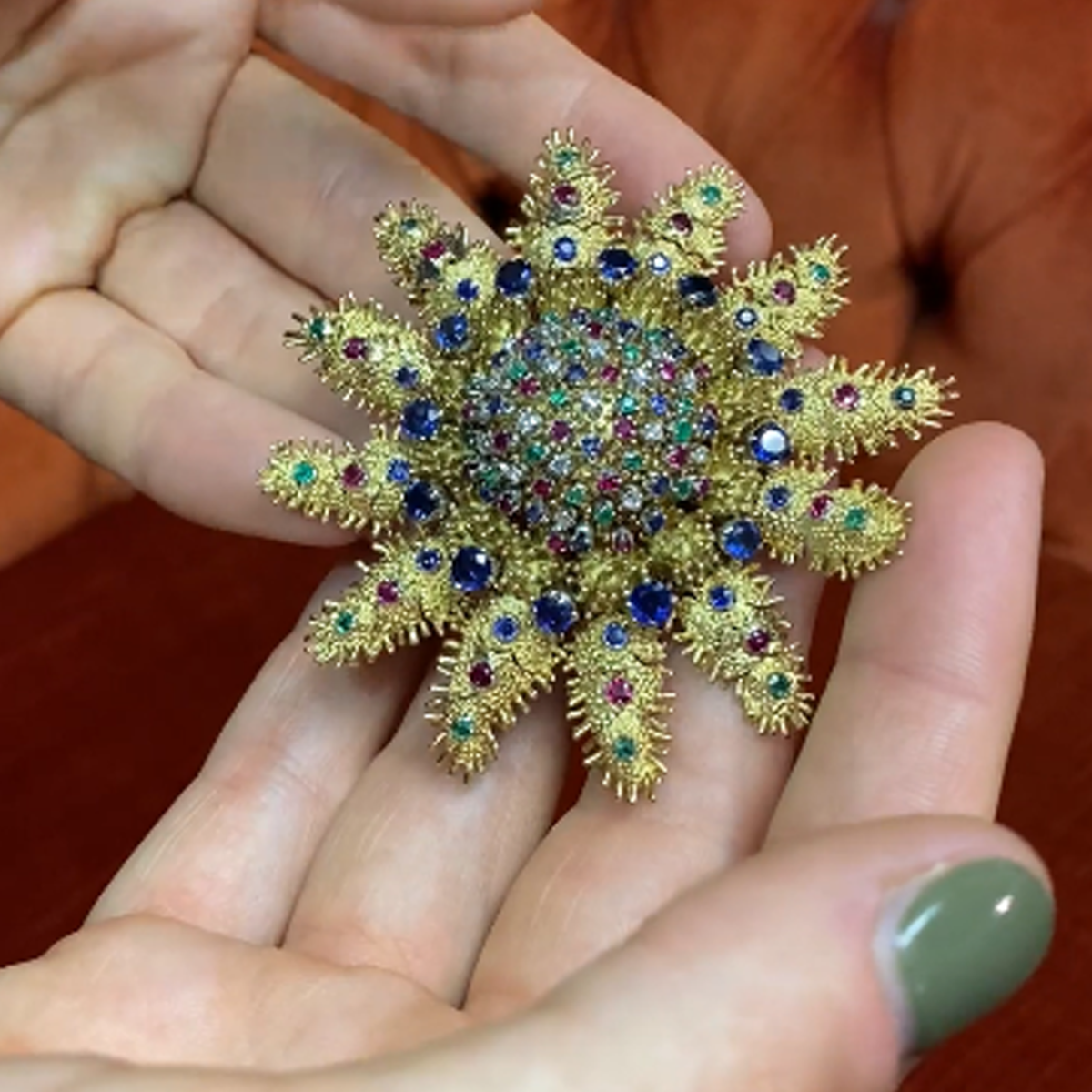 1960s 18KT Yellow Gold Diamond, Emerald, Ruby & Sapphire Articulated Starfish Brooch in hand